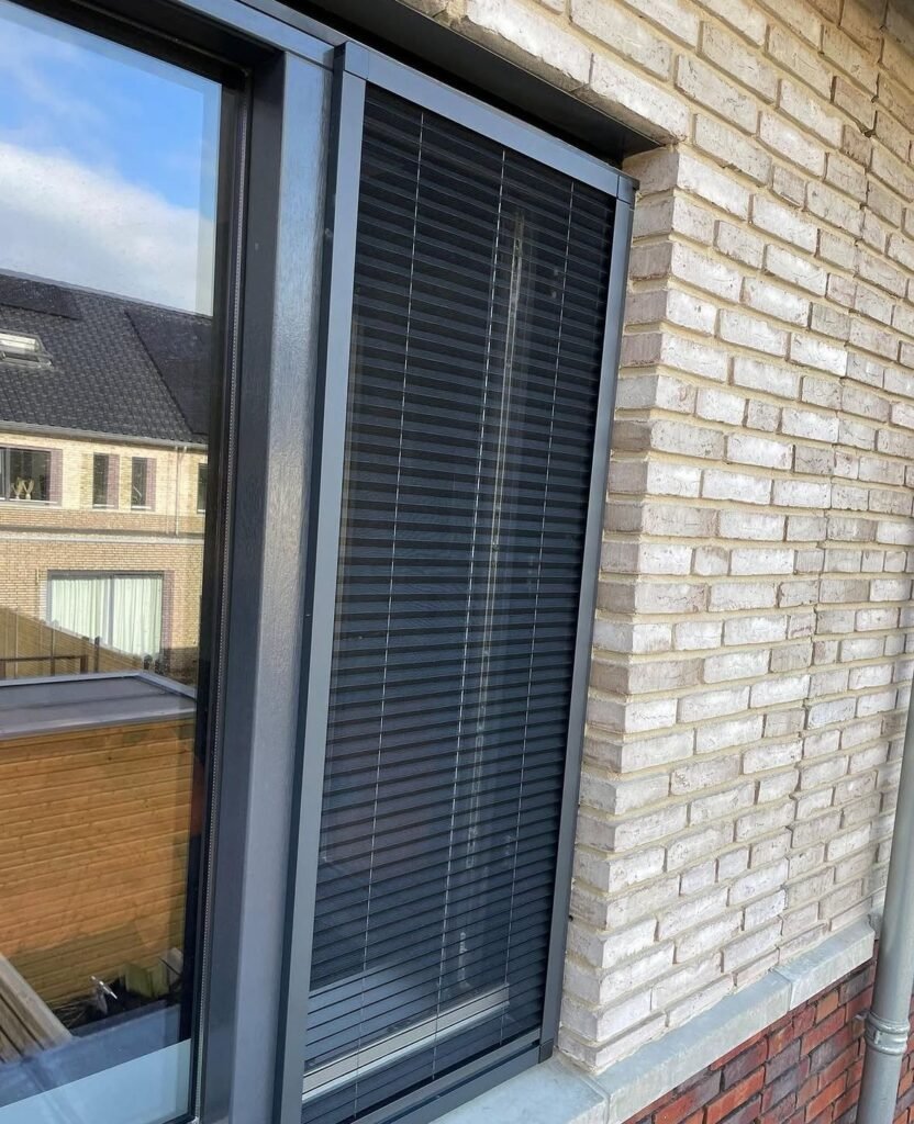 Antraciet plissé hor in een raam van een bakstenen gevel