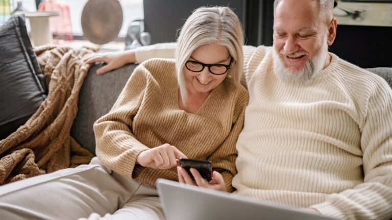 Stel op de bank bekijkt samen rolluiken op de telefoon en laptop